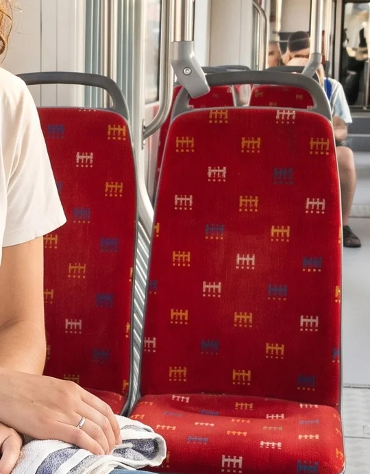 Detail vygenerovaného poťahu: ten istý znak v bielej, zlatej a modrej farbe na červenom podklade.